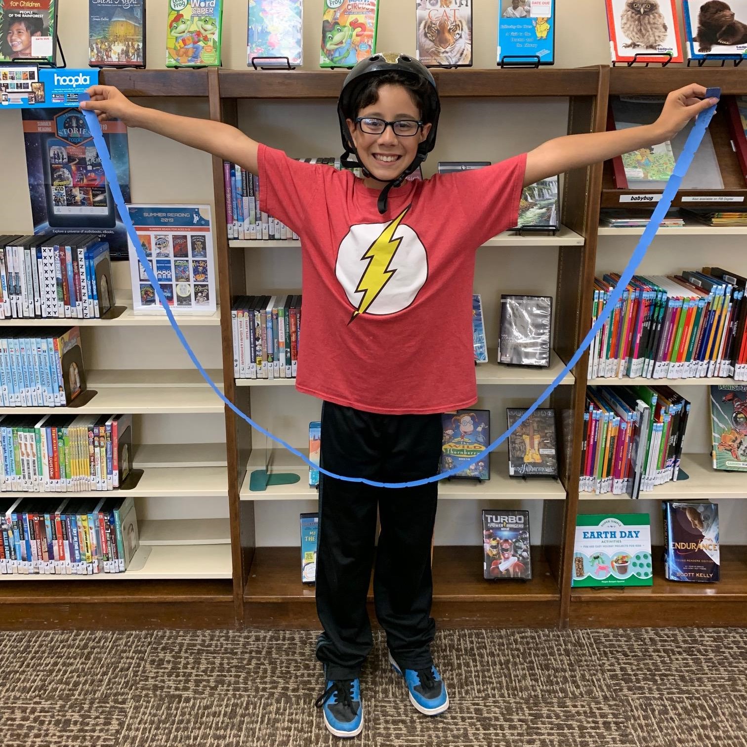 Photo of child holding the tickets he got for all the books he read that summer